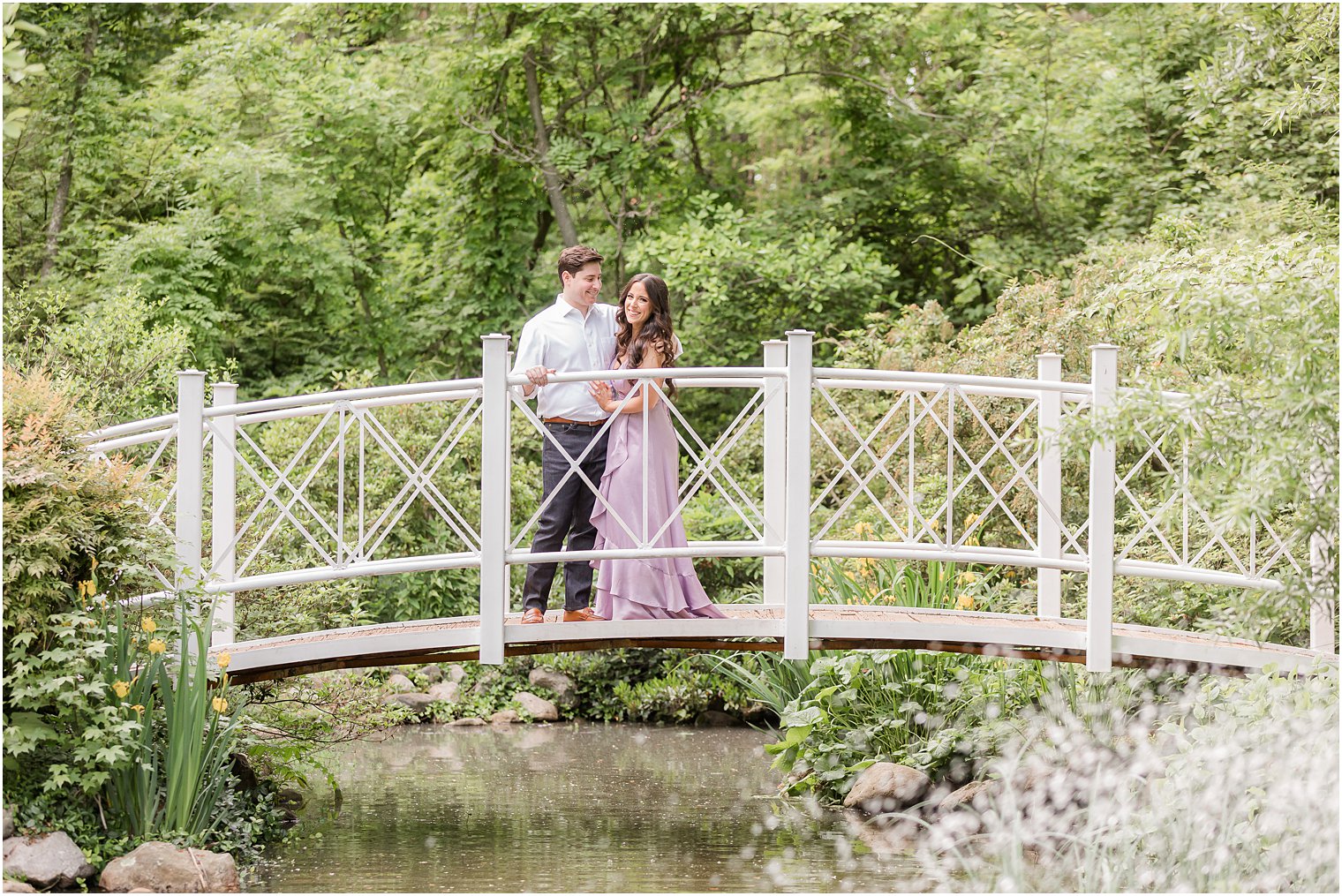 bride and groom hug on bridge during Sayen Gardens engagement session