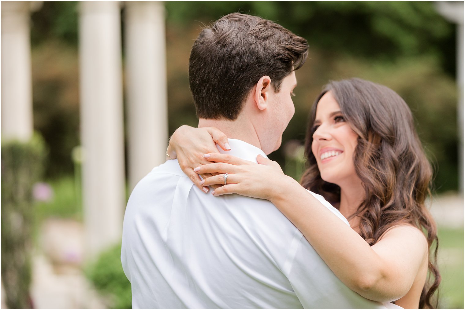 woman hugs man and smiles up at him in front of gazebo 