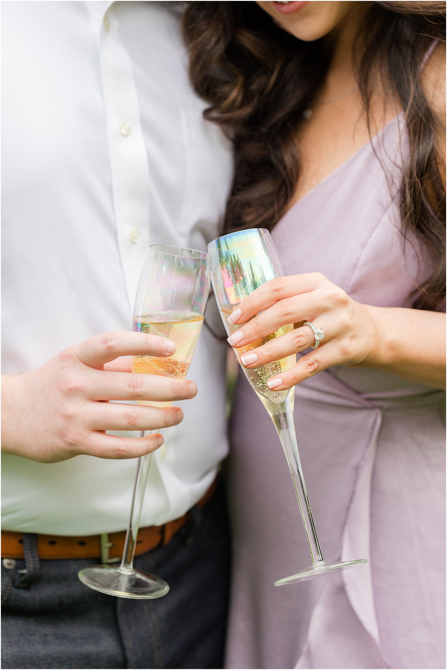woman with brown hair in purple dress toasts champagne with man in white button down shirt