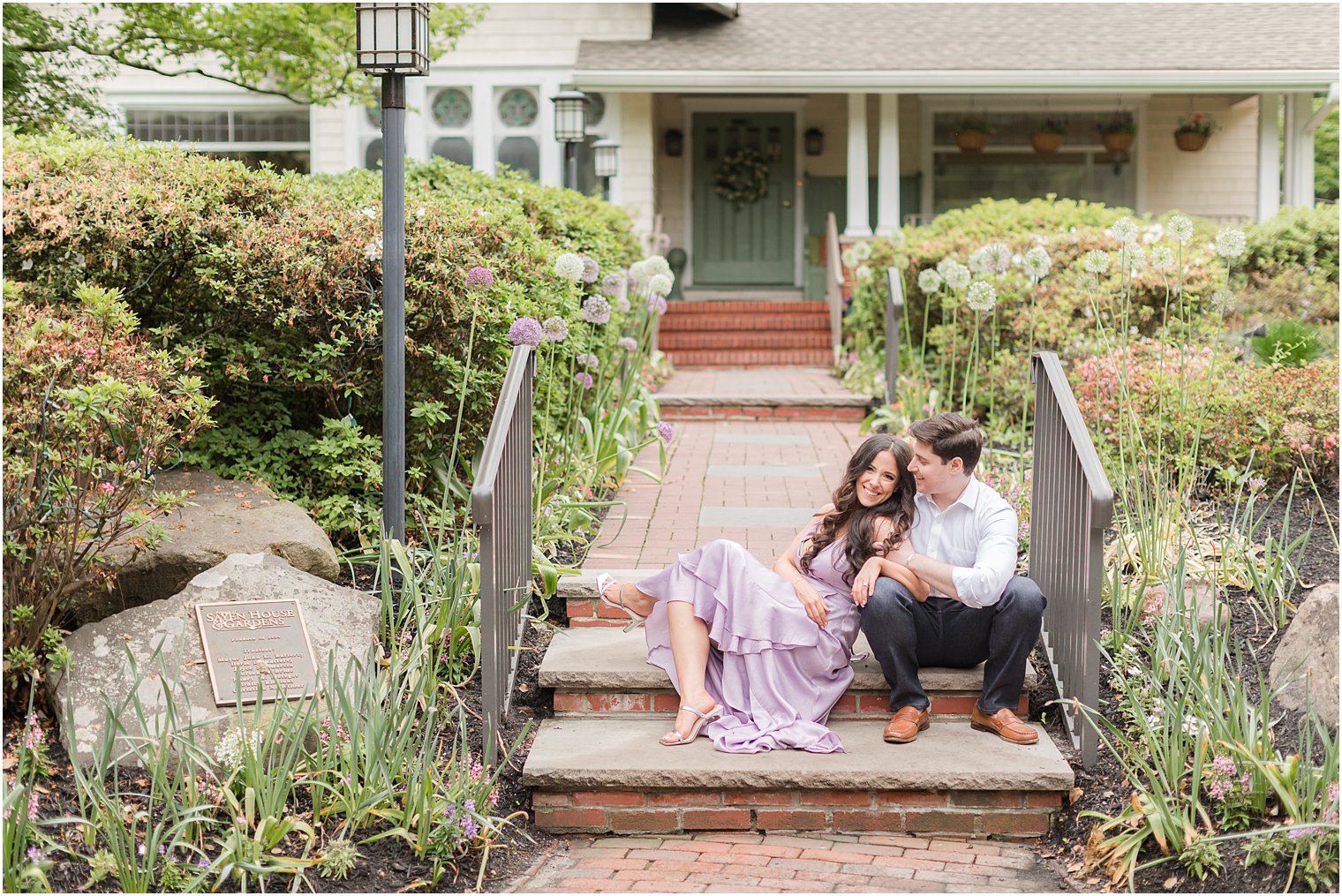 engaged couple sits on steps in front of house in Hamilton NJ park 