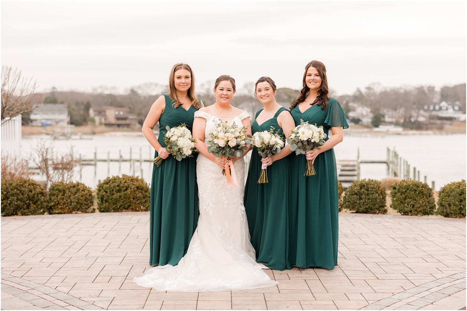 bride stands with three bridesmaids in teal gowns at Crystal Point Yacht Club