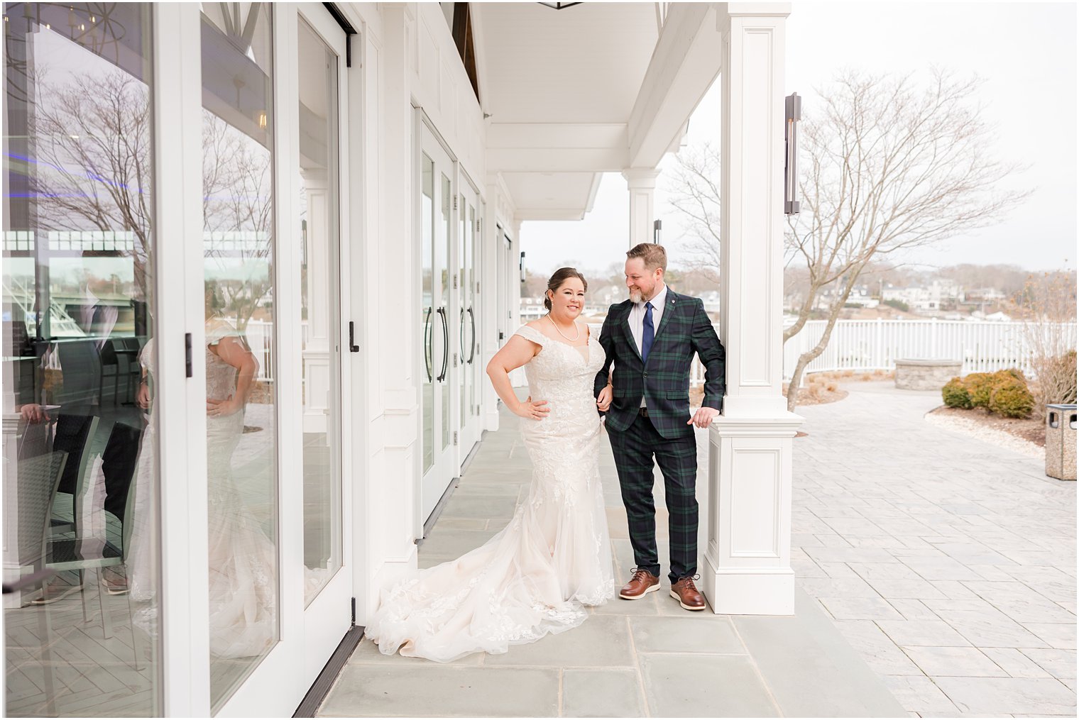 newlyweds stand against white pillar at Crystal Point Yacht Club