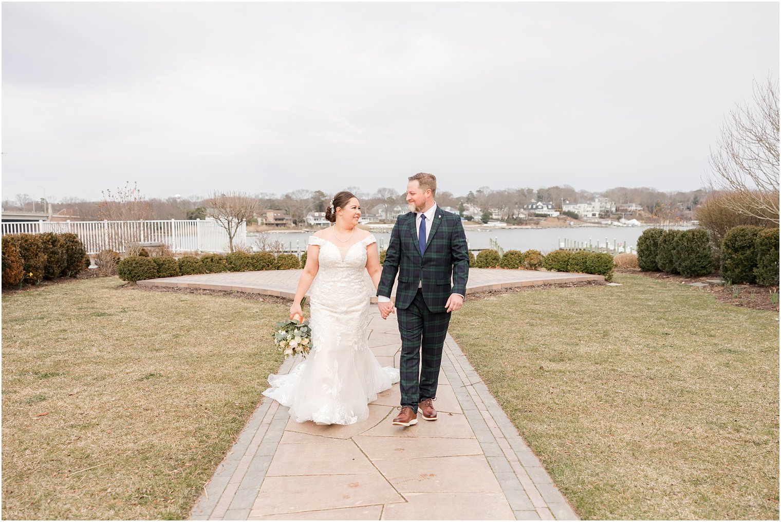 bride and groom hold hands walking on brick pathway at Crystal Point Yacht Club