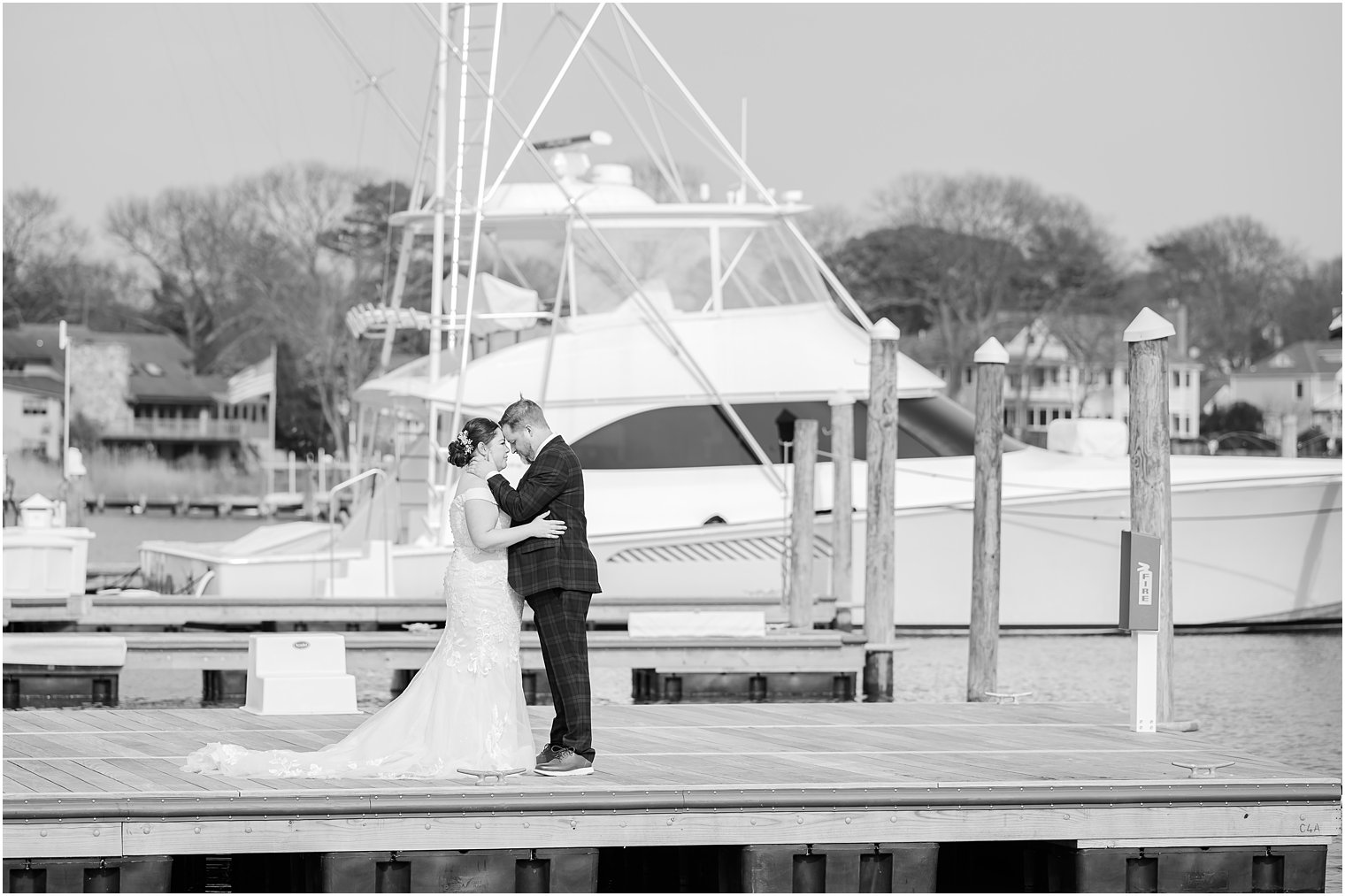 bride and groom hug by boats in marina 