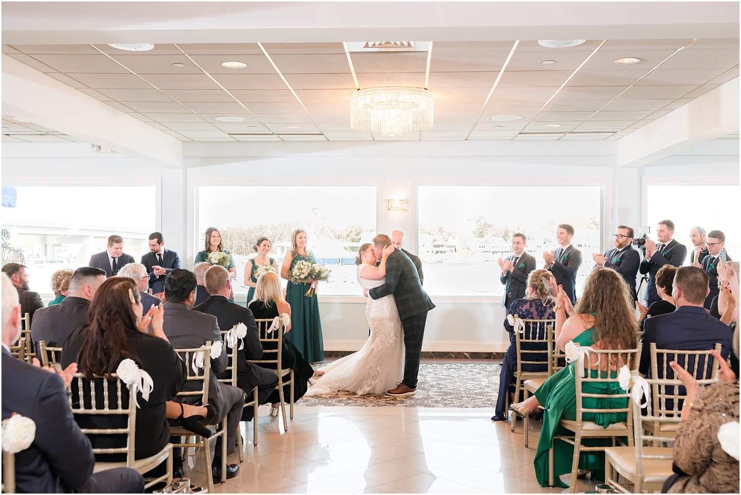 bride and groom kiss during wedding ceremony with waterfront views at Crystal Point Yacht Club