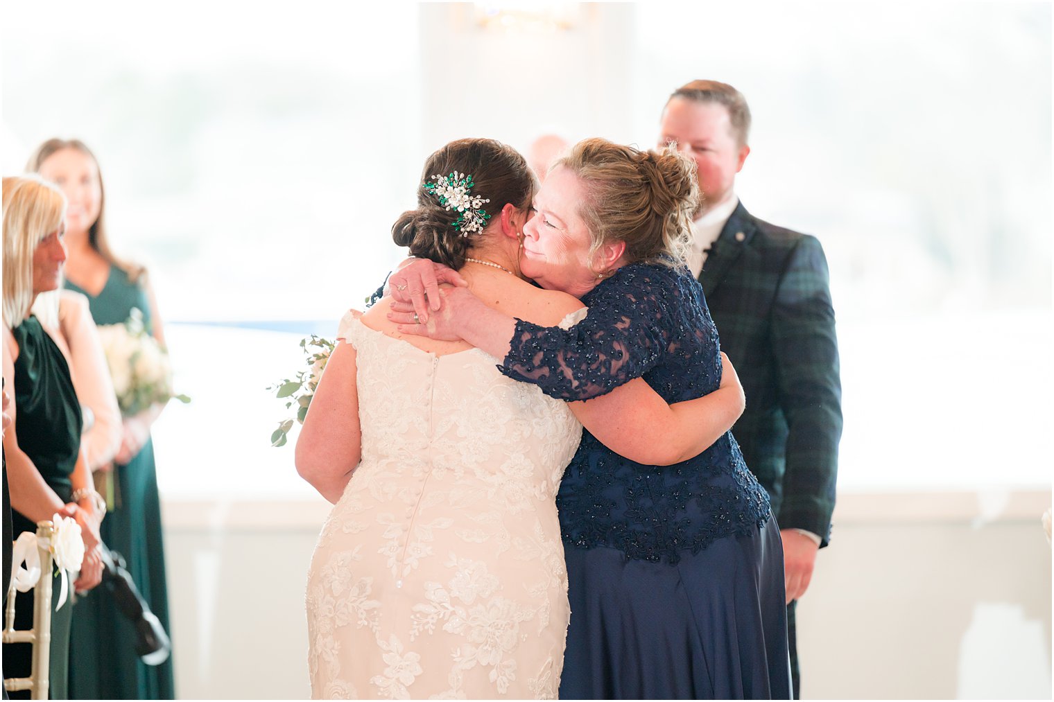 mom hugs bride during wedding ceremony with waterfront views at Crystal Point Yacht Club