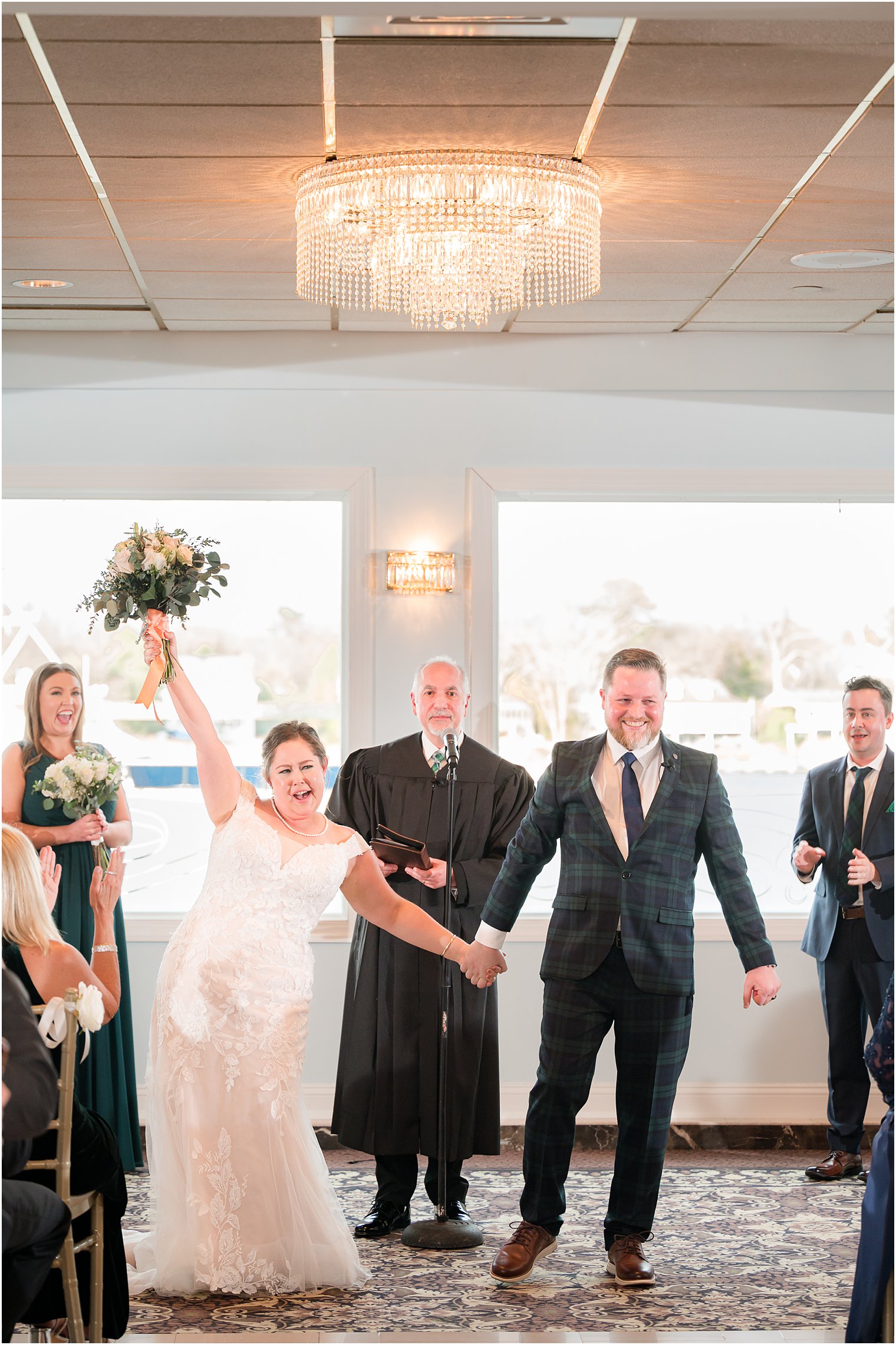couple cheers leaving wedding ceremony with waterfront views at Crystal Point Yacht Club