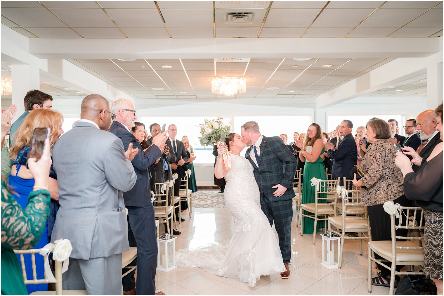 newlyweds kiss leaving wedding ceremony with waterfront views at Crystal Point Yacht Club