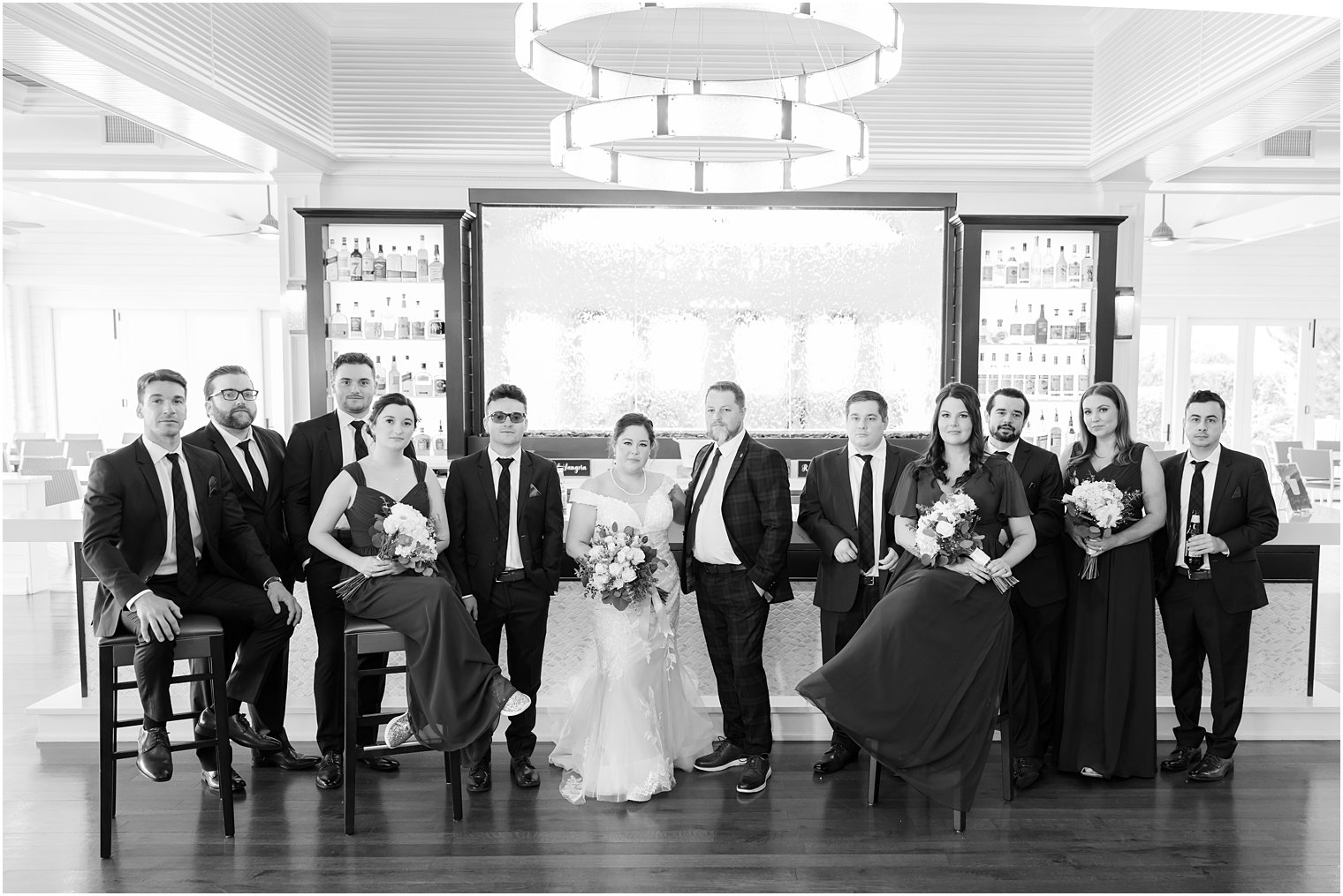 bride and groom stand with wedding party at bar at Crystal Point Yacht Club