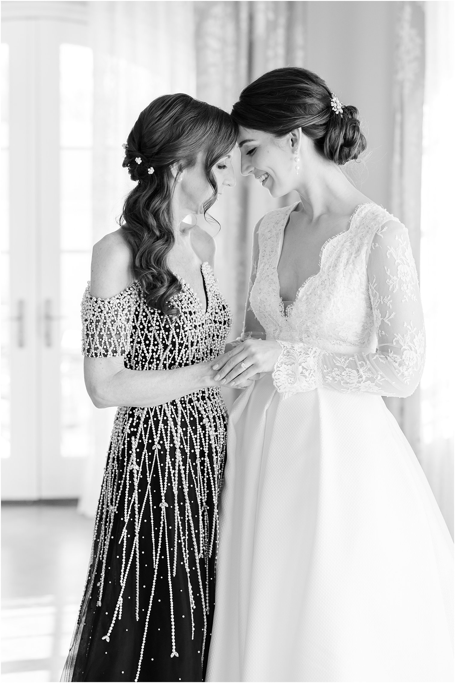 black and white photo of bride and mother leaning heads together 