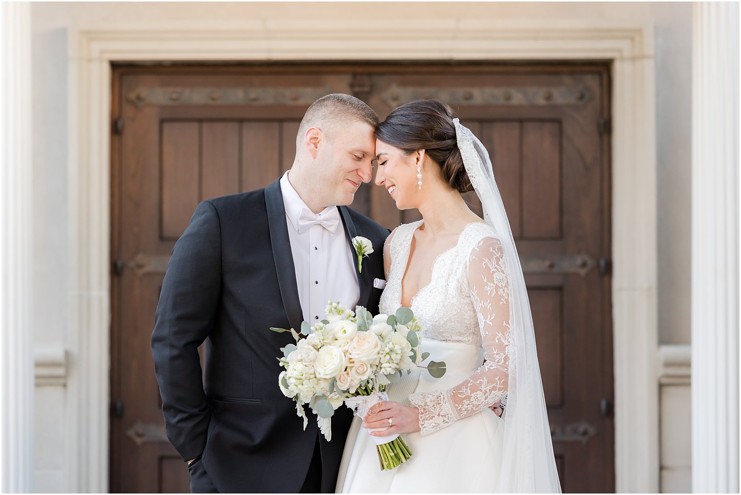 bride and groom lean heads together by wooden door at Park Chateau Estate