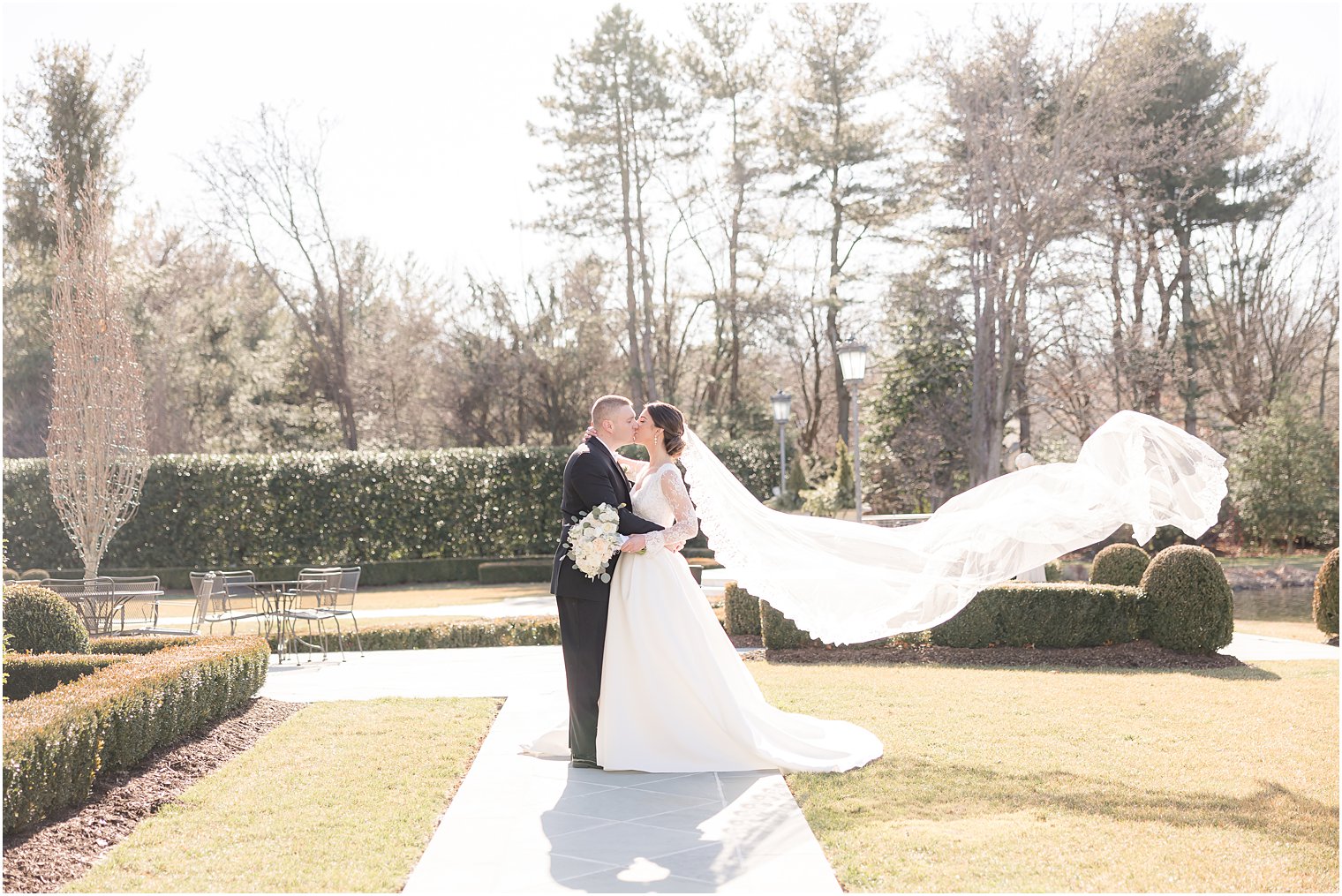 newlyweds kiss with bride's veil floating behind her at Park Chateau Estate