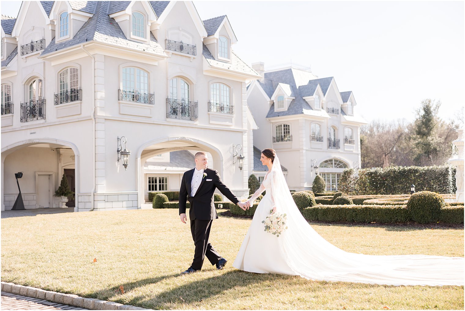 groom in black suit leads bride across lawn at Park Chateau Estate