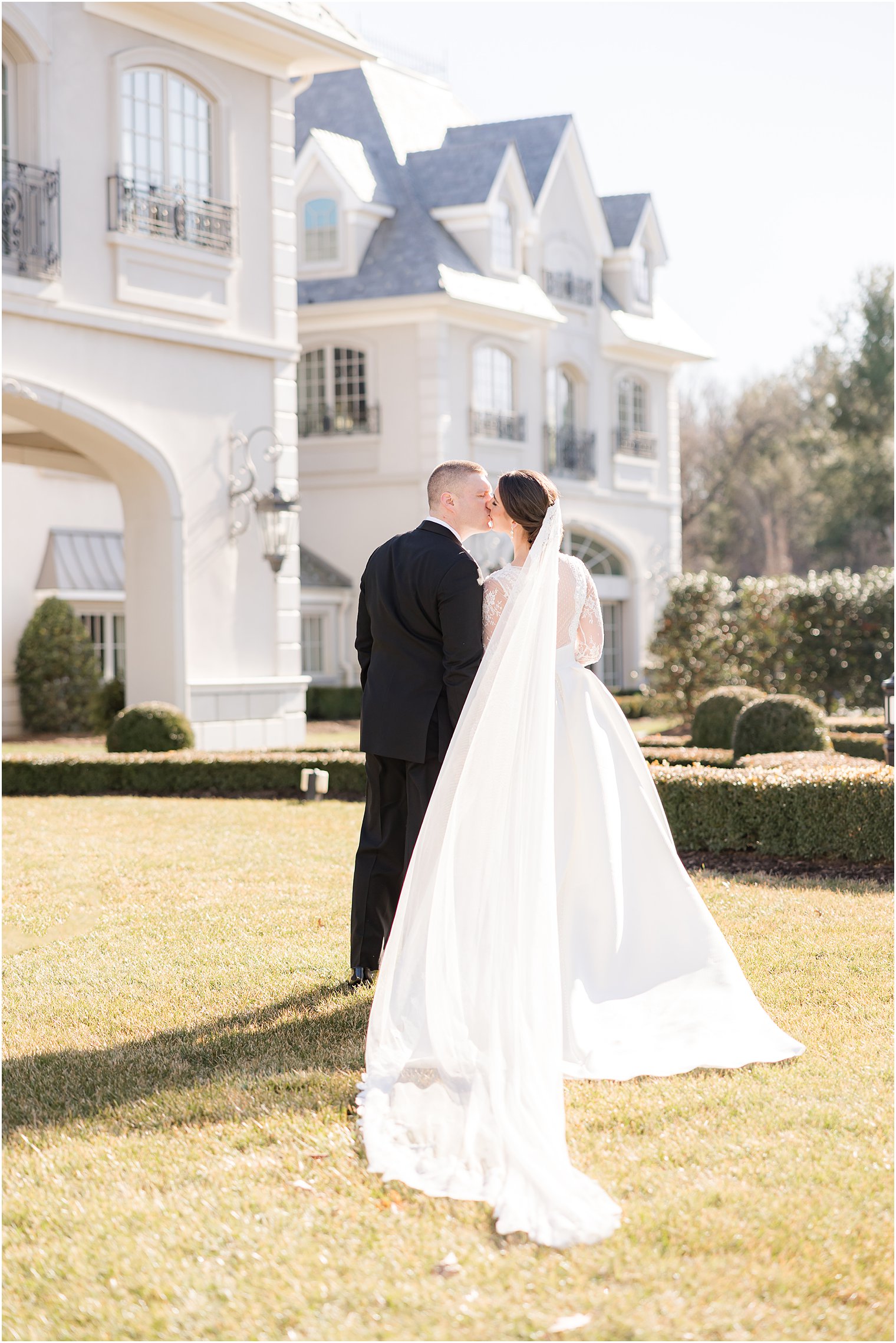 bride and groom kiss on lawn in front of Park Chateau Estate