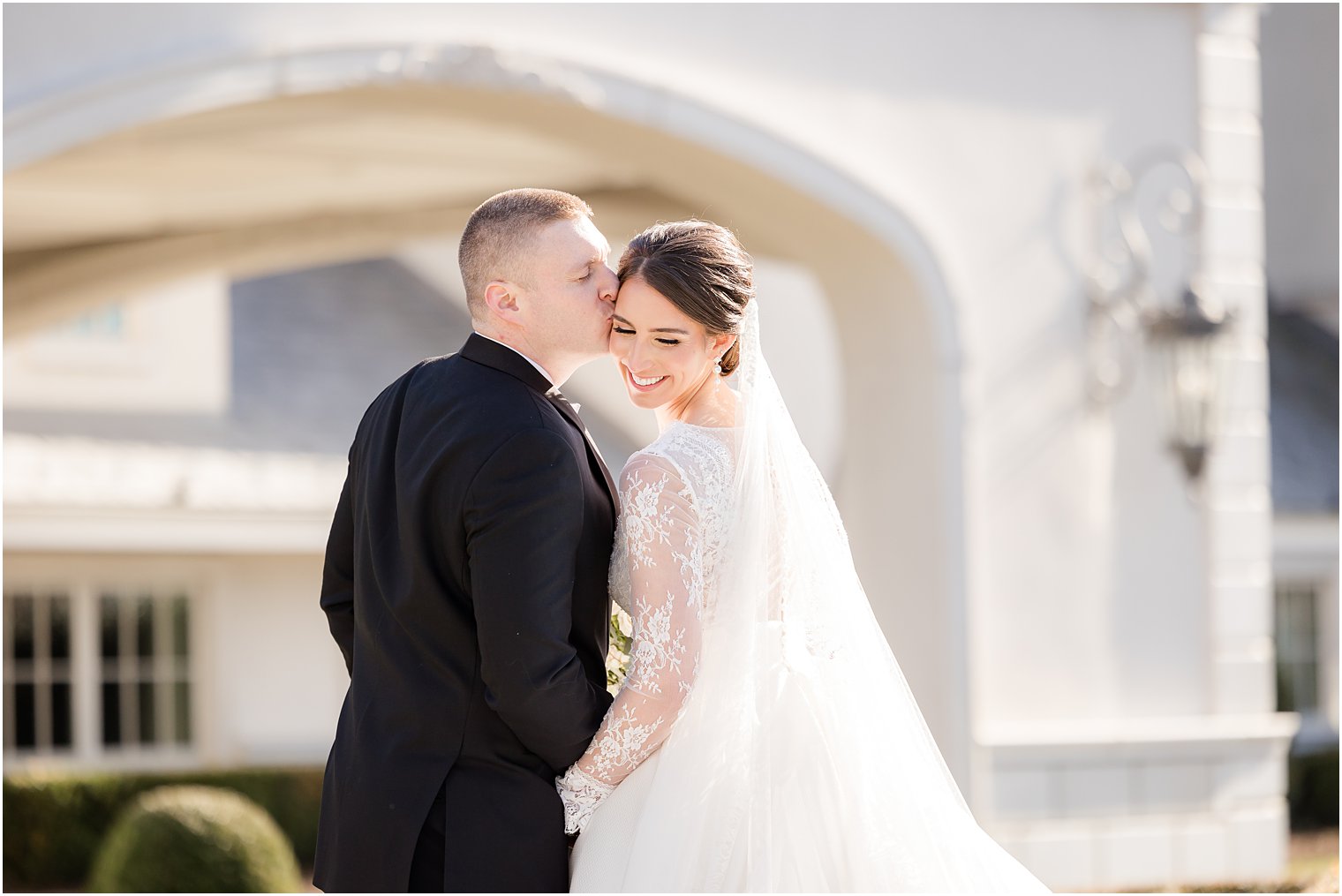 groom leans to kiss bride's cheek outside Park Chateau Estate