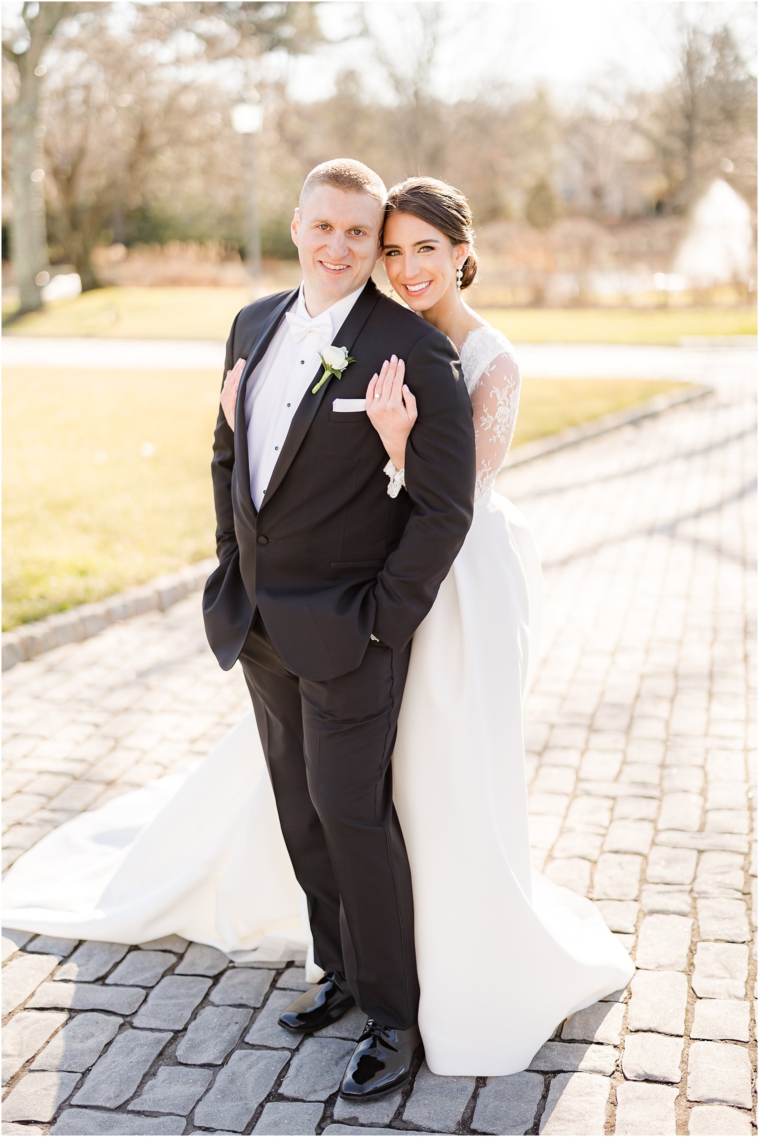 bride hugs groom from behind on walkway at Park Chateau Estate