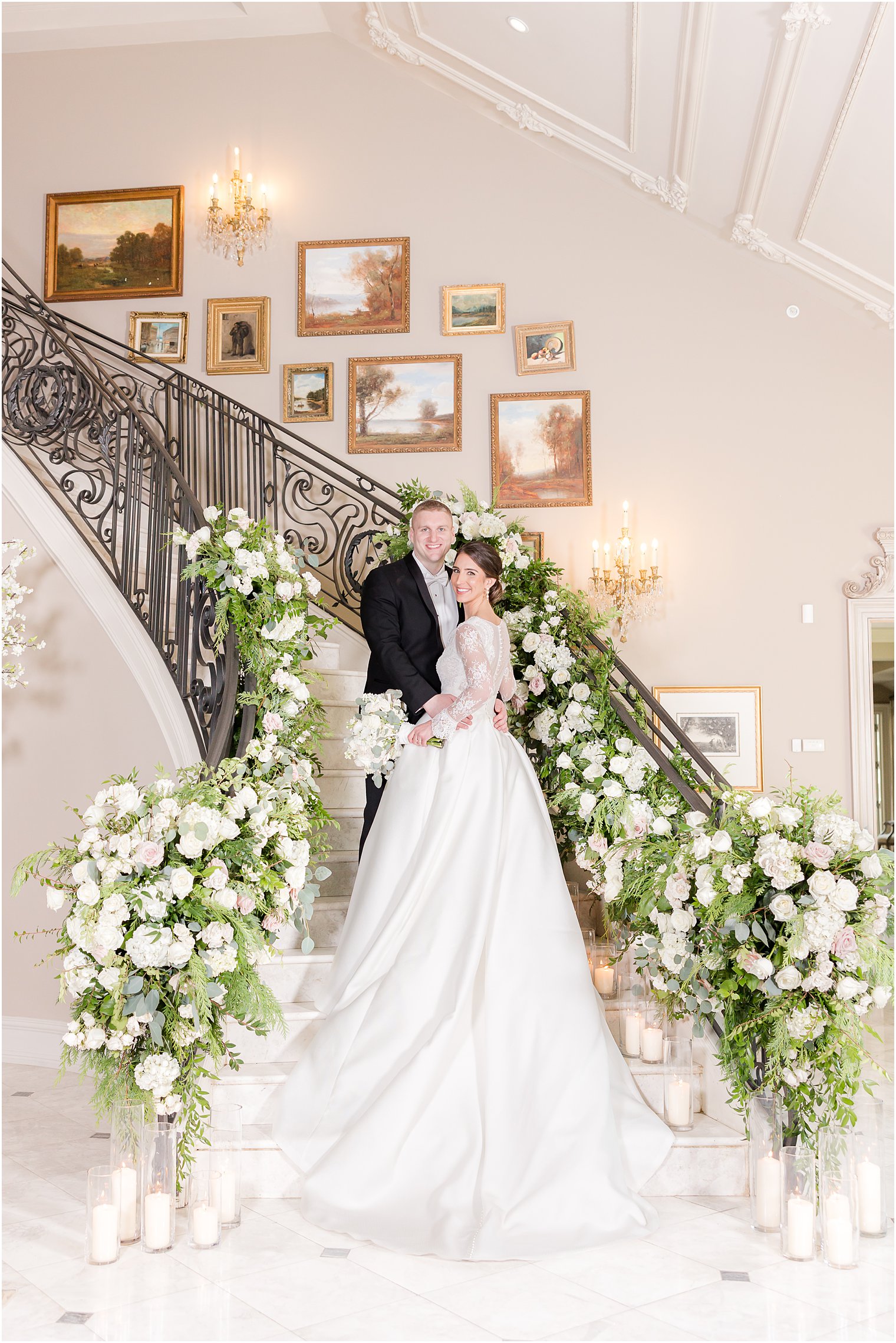 bride and groom hug on staircase in Park Chateau Estate covered in white flowers 