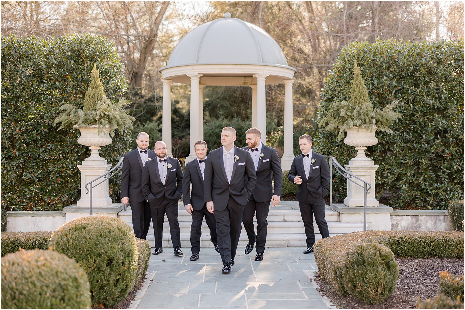 groom and groomsmen walk in gardens at Park Chateau Estate