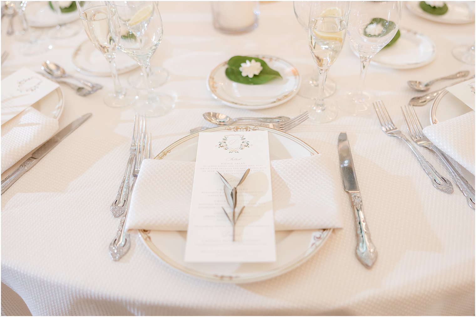 white plate with silverware and green sprig on napkin