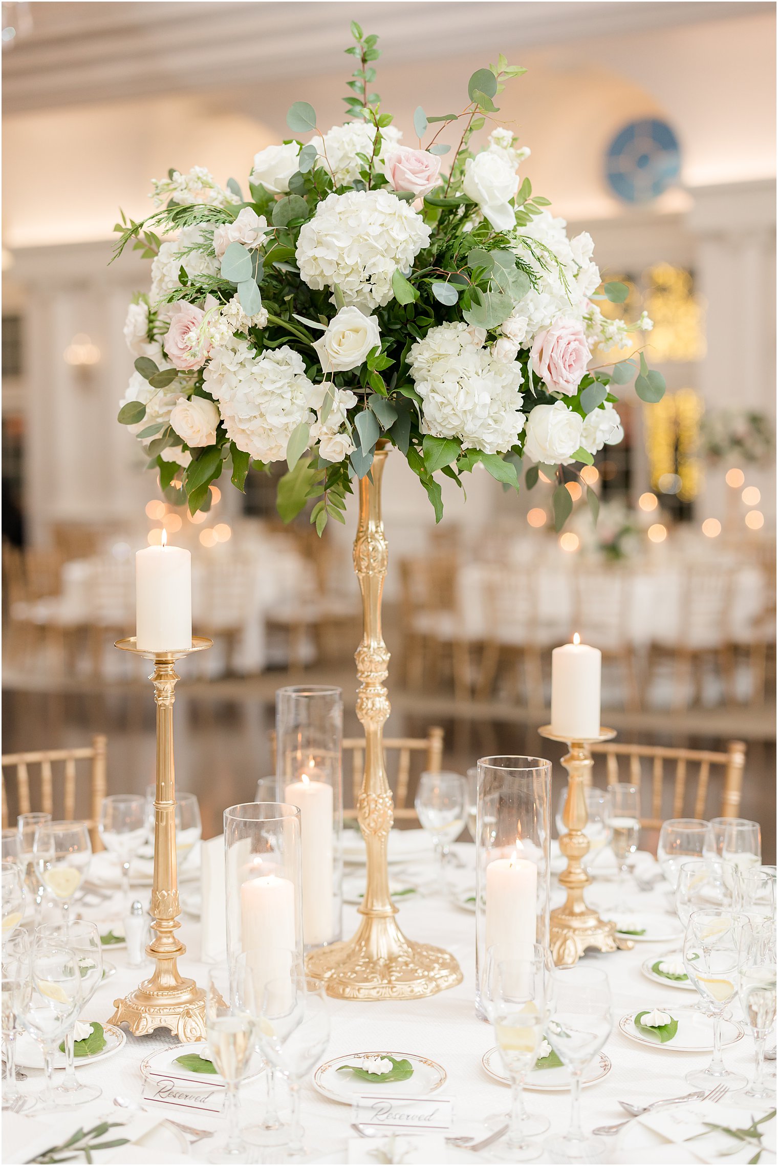 tall floral centerpiece in gold vase with white roses