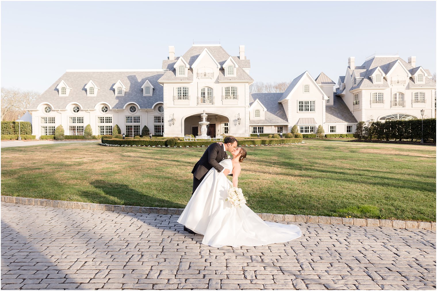 bride and groom kiss in front of Park Chateau Estate