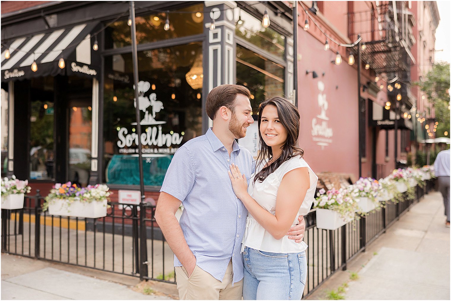 engaged couple hugs on corner of street in Hoboken NJ