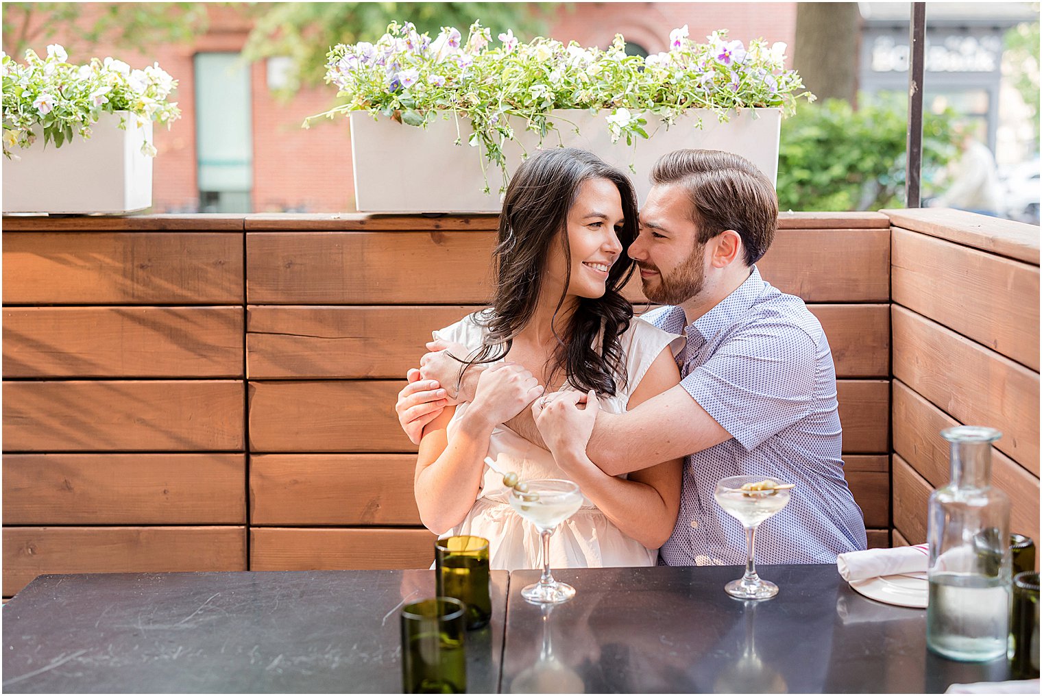 man in blue shirt hugs fiancee sitting at restaurant in New Jersey