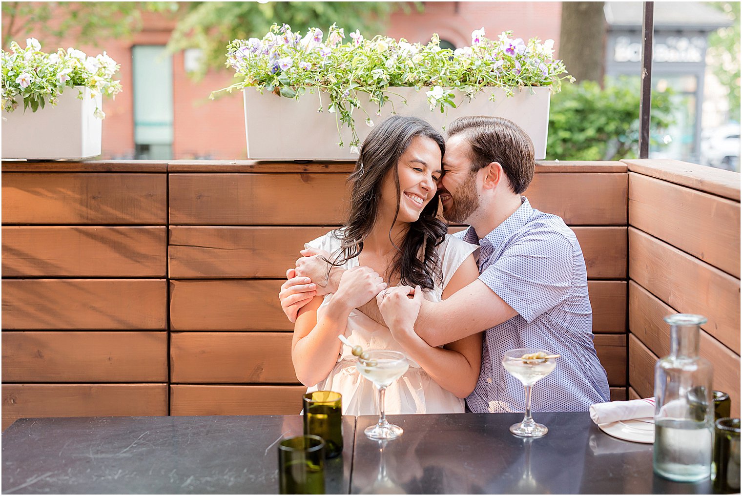 couple hugs sitting for drinks during Hoboken engagement session