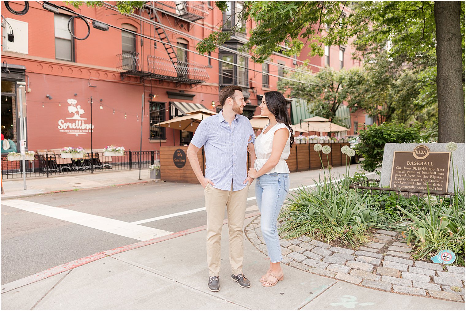 engaged couple stands on sidewalk and street corner during Hoboken engagement session