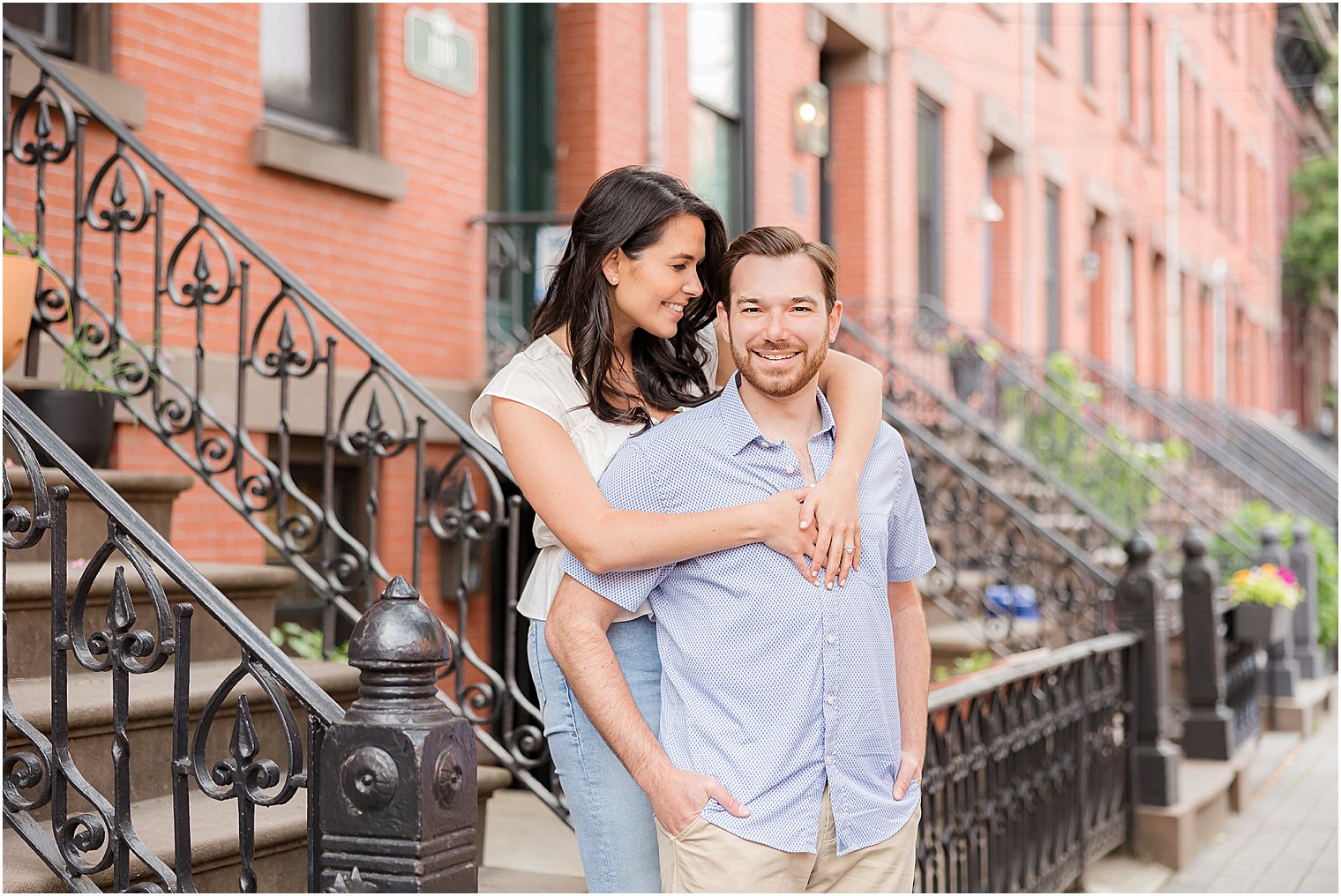 woman hugs fiance in front of brownstones in Hoboken NJ