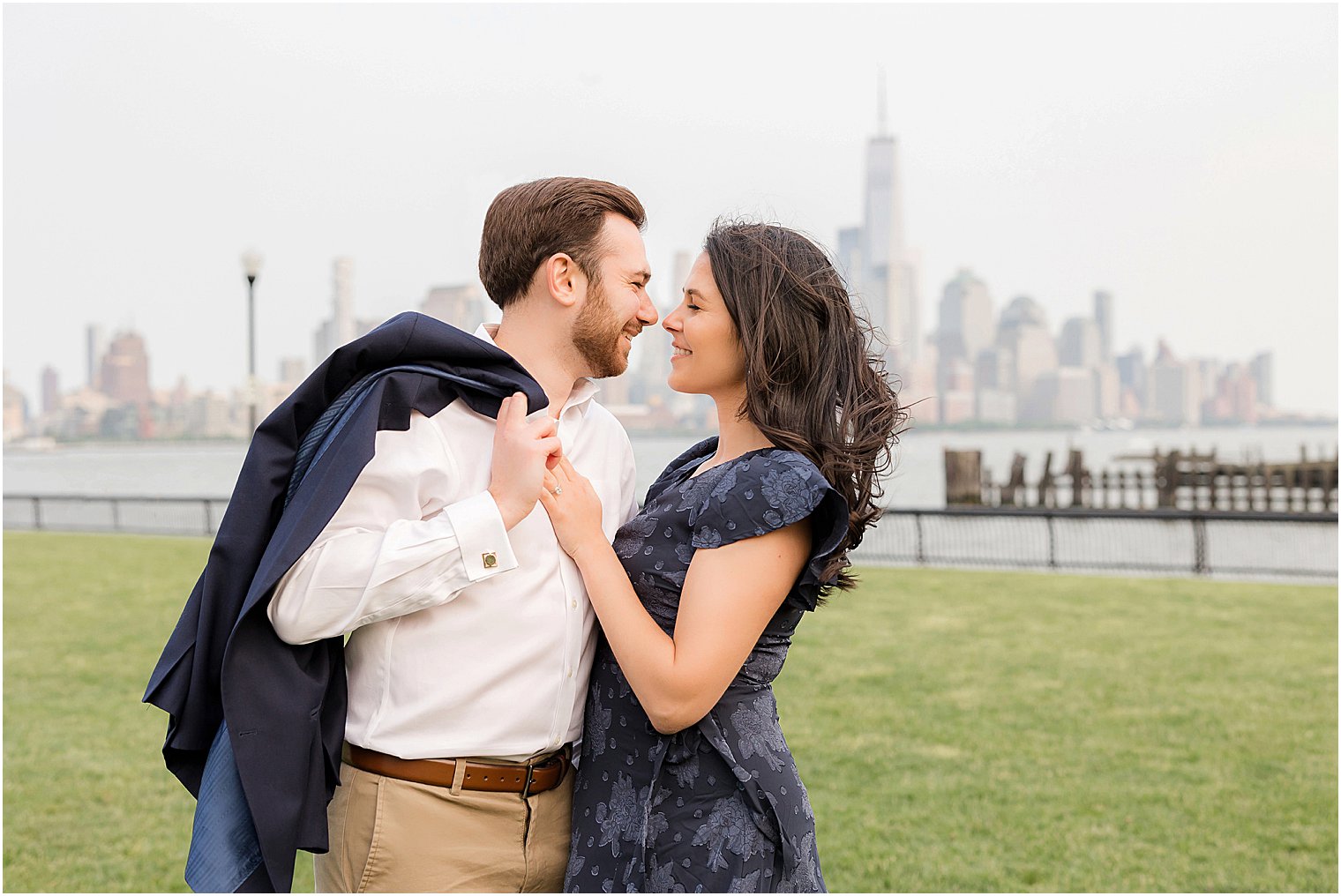 engaged couple leans together with man's jacket over shoulder 