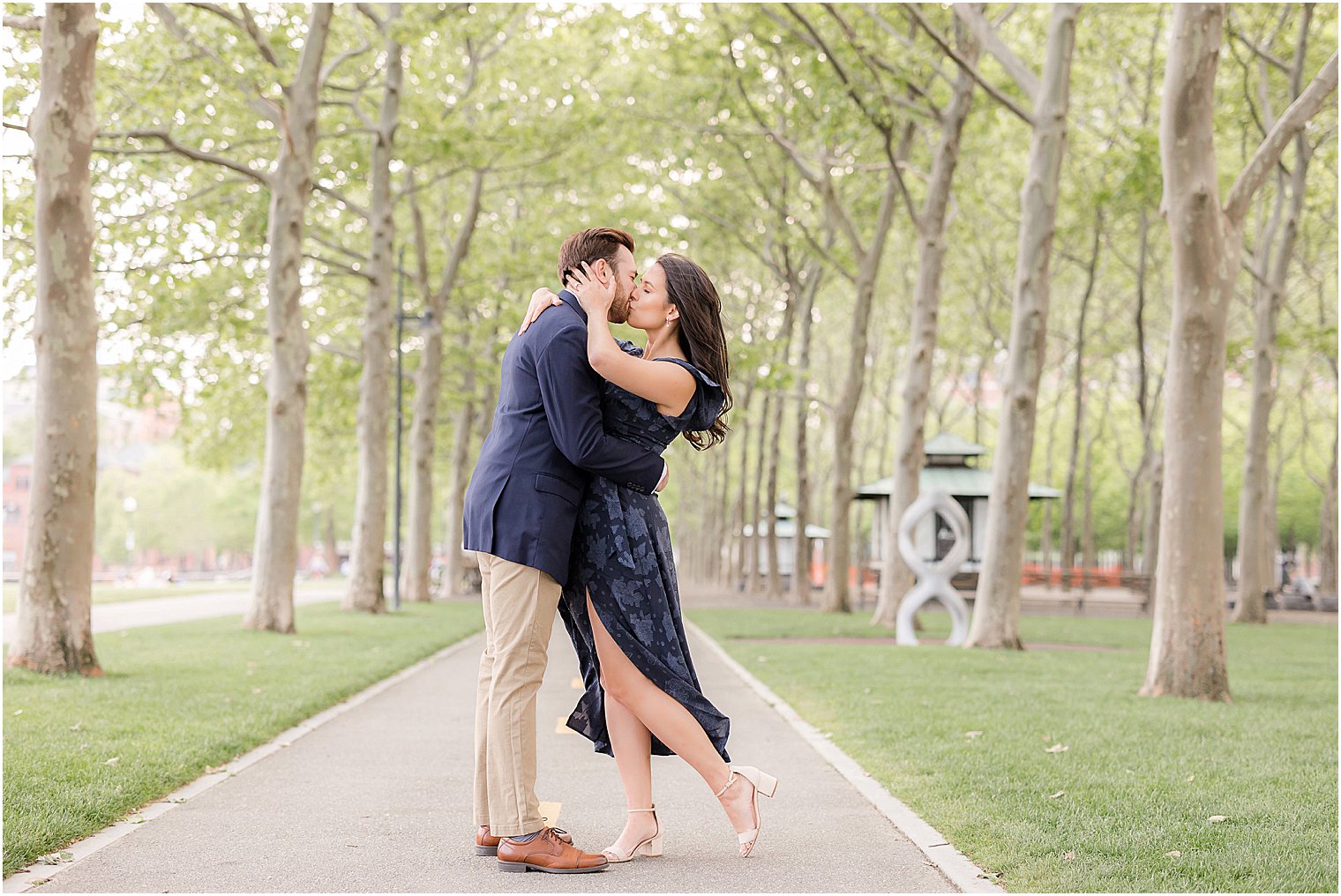 woman holds man's cheek kissing him in Hoboken NJ park