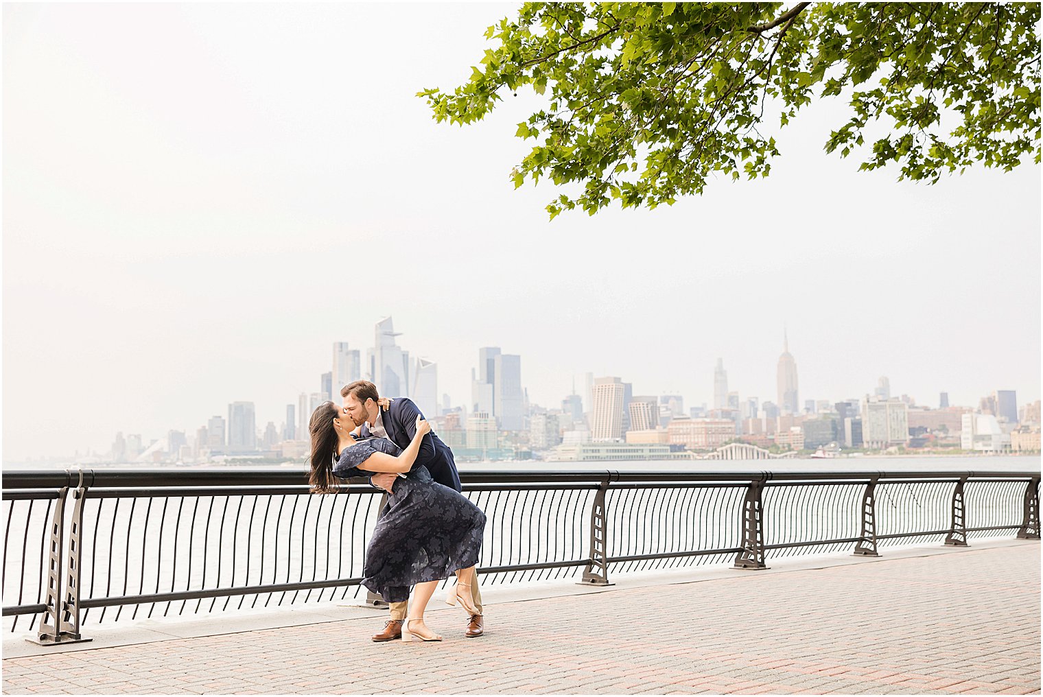 engaged couple kisses by NYC skyline in New Jersey park