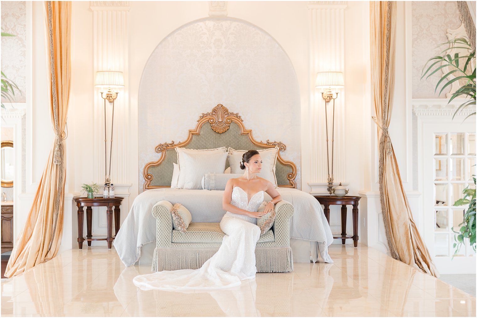 bride sits on couch at end of bed in suite at Mallard Island Yacht Club