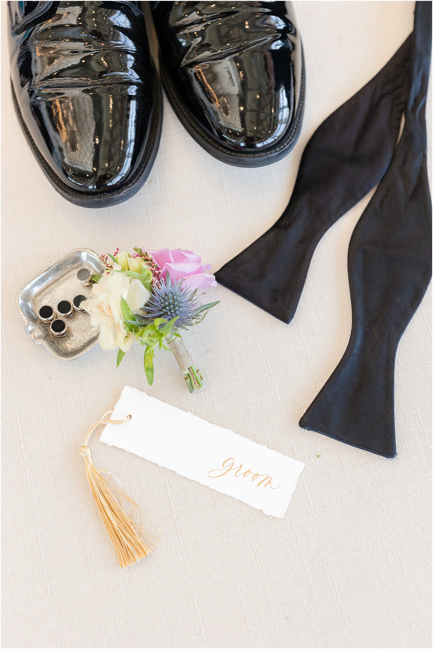 groom's tag with pink boutonniere and black shoes