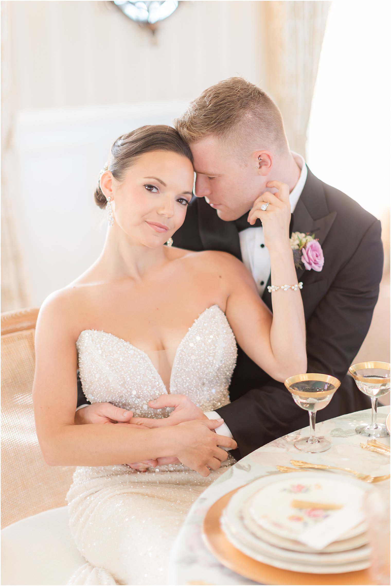 groom nuzzles bride's cheek sitting at table at Mallard Island Yacht Club