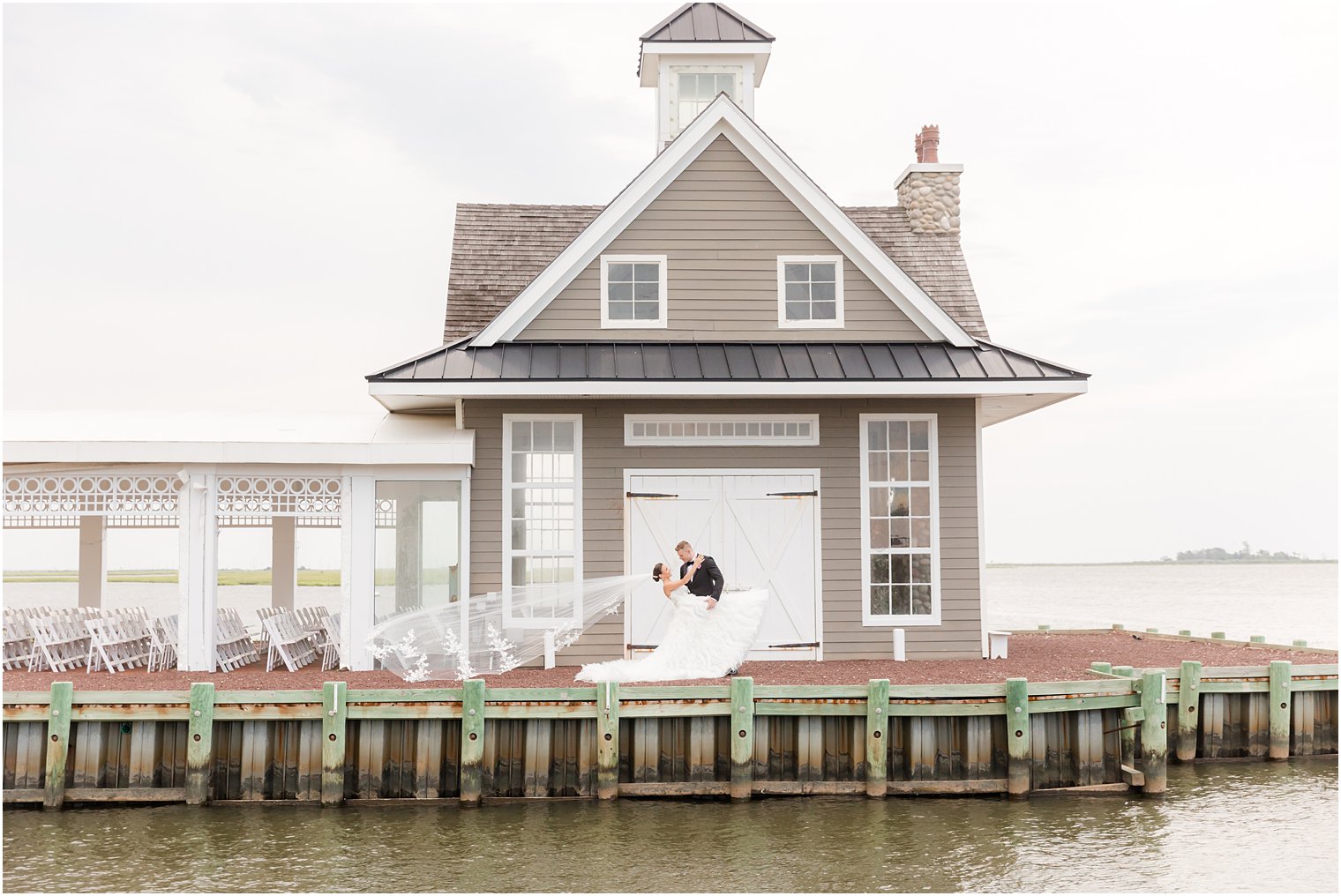 groom dips bride with veil floating behind her at Mallard Island Yacht Club