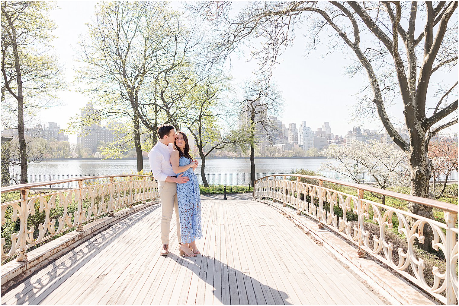 engaged couple hugs on bridge in Central Park at sunrise 