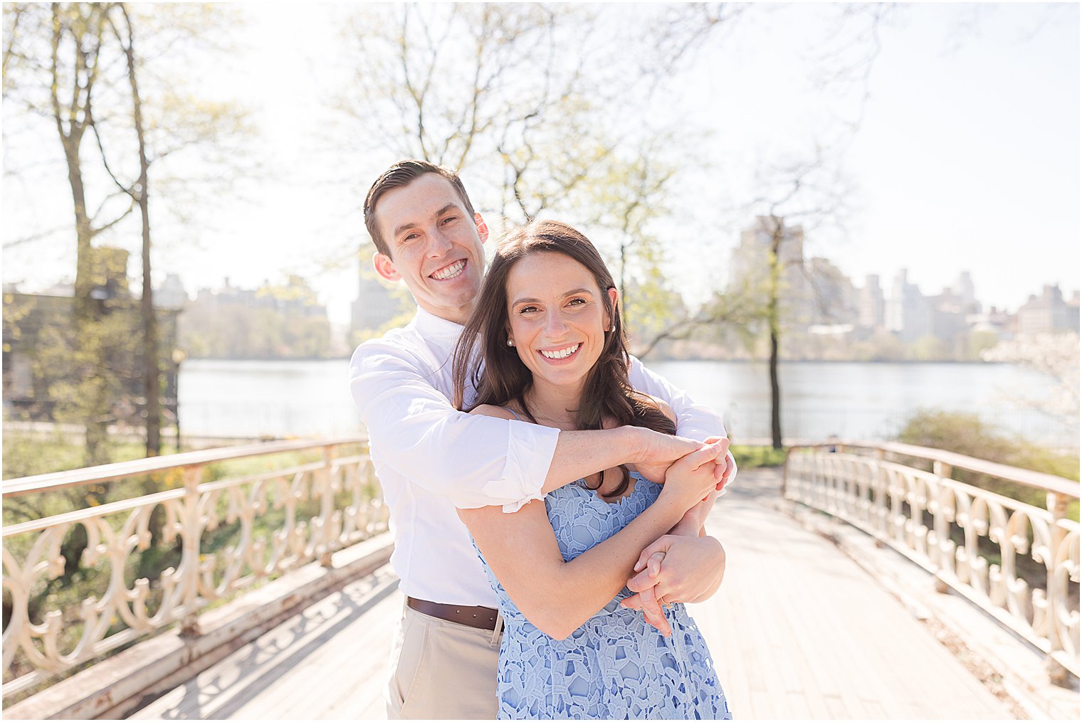 man hugs woman on bridge in Central Park during New York City engagement session