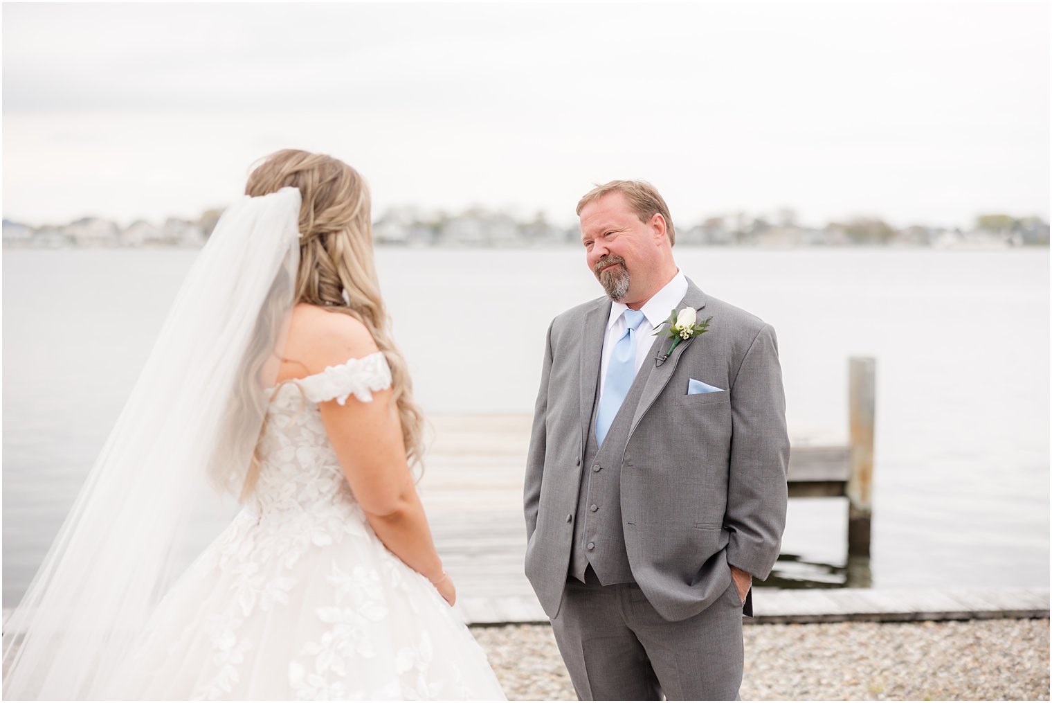 dad smiles at bride during emotional first look near water 