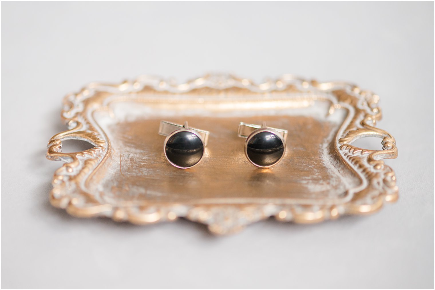 groom's black and gold cufflinks on gold tray