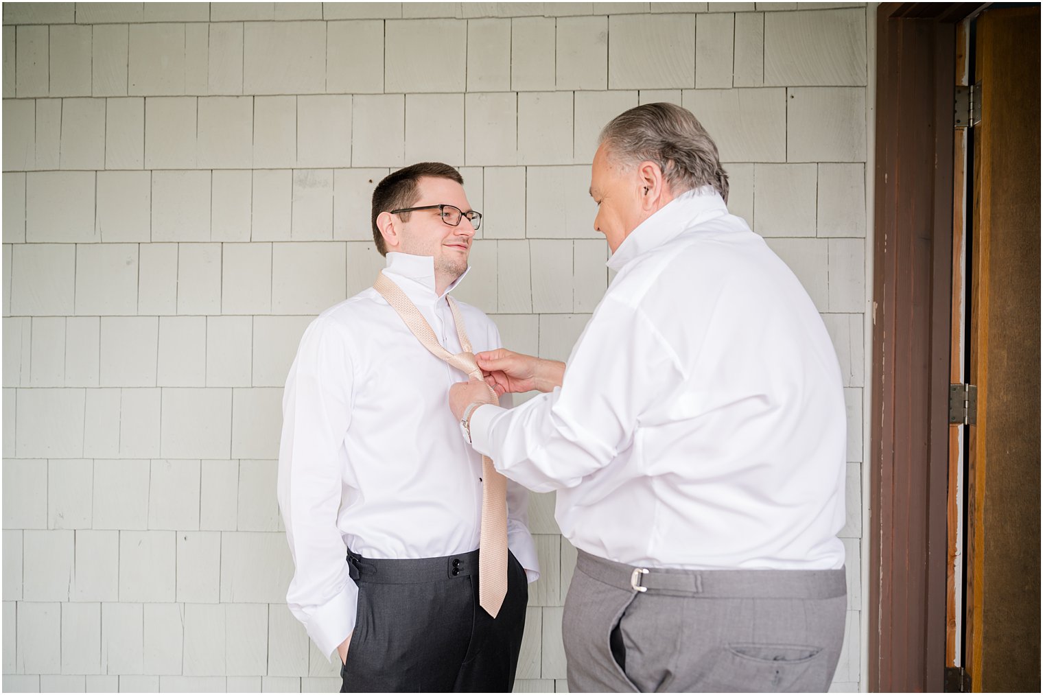 father helps groom with tie on morning of wedding