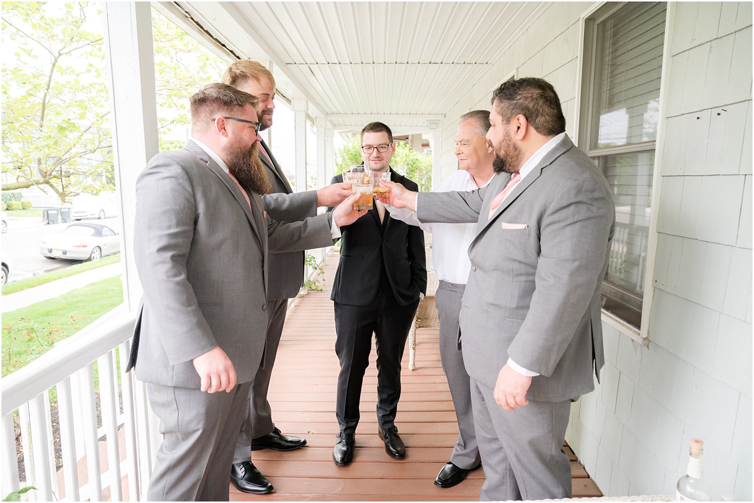 groom and groomsmen toast glasses on front porch of NJ home