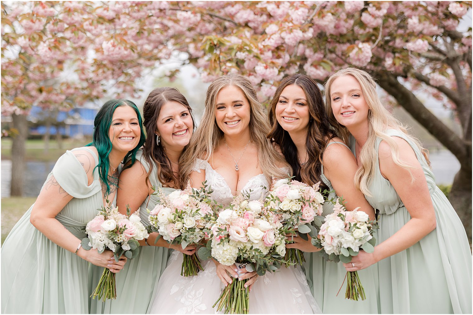 bridesmaids hug close to bride in Divine Park in Spring Lake NJ