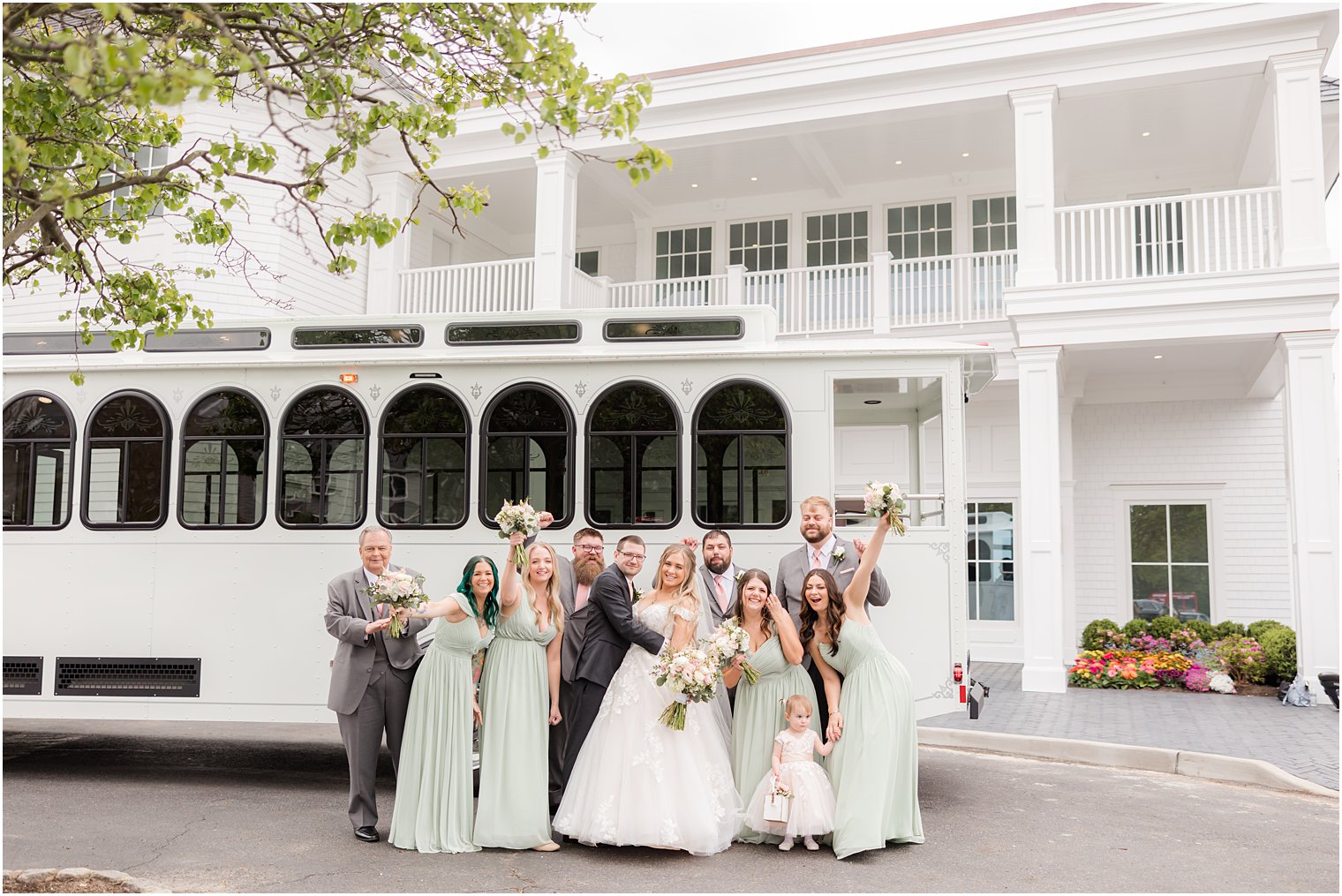 bride and groom hug with wedding party outside trolley and Clark's Landing Yacht Club