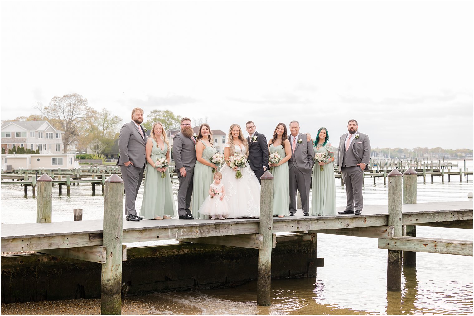 newlyweds pose with wedding party on dock at Clark's Landing Yacht Club