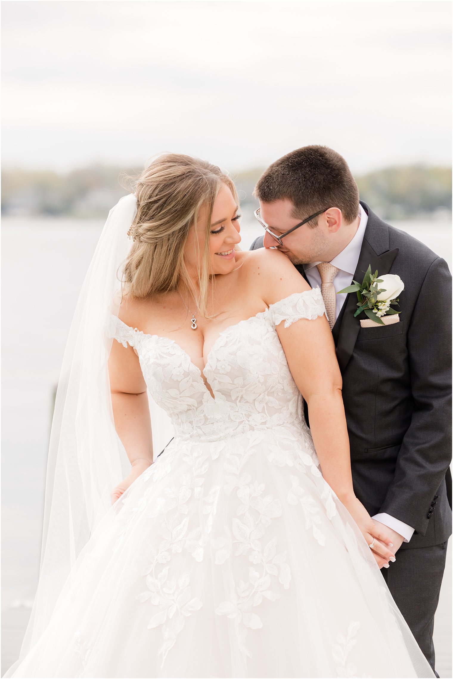 groom kisses bride's shoulder on dock