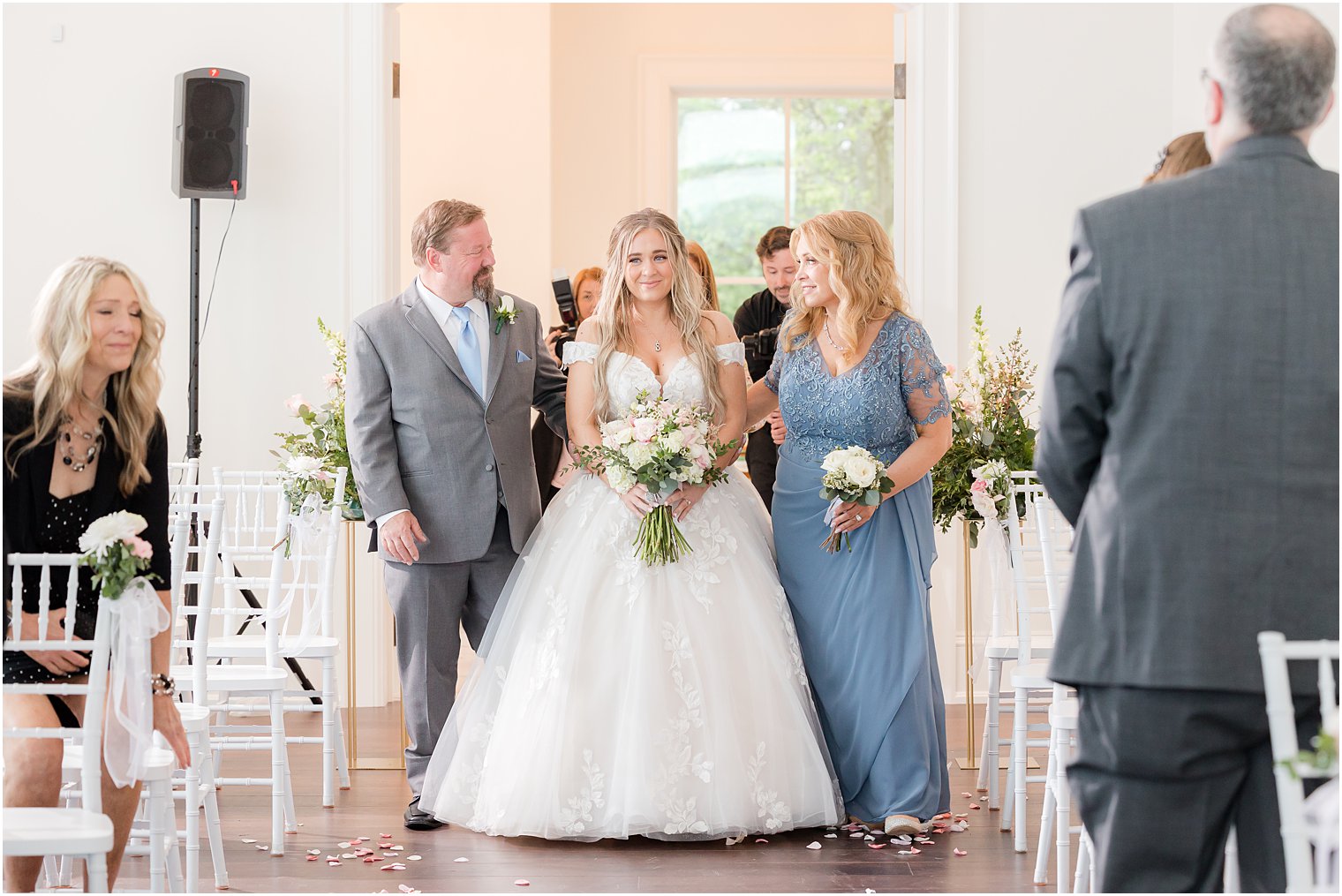 bride walks down aisle with parents for Clark's Landing Yacht Club wedding ceremony