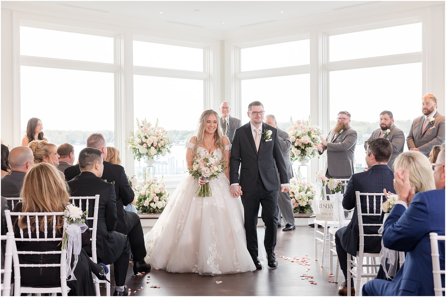 bride and groom hold hands leaving Clark's Landing Yacht Club wedding ceremony