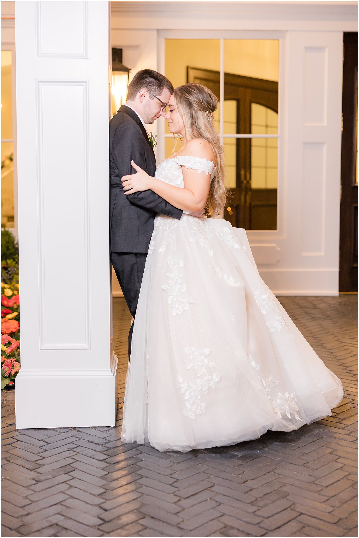 bride and groom lean heads together leaning against white pillar at Clark's Landing Yacht Club